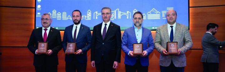 Program afişinin önünde plaket alan katılımcılar