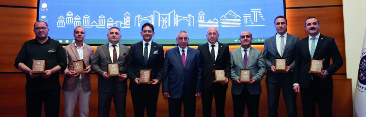 Program afişinin önünde plaket alan katılımcılar