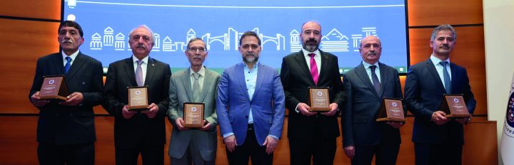 Program afişinin önünde plaket alan katılımcılar