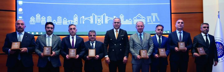 Program afişinin önünde plaket alan katılımcılar