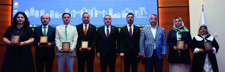 Program afişinin önünde plaket alan katılımcılar